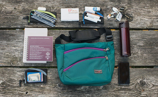 A possible loadout for an Icon -- a water bottle, keys, a couple of organizer pouches, an A5 pad of paper and a cellphone.